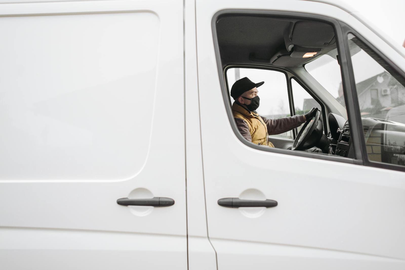 commercial auto A delivery driver wearing a face mask operates a van, embodying modern safety measures.